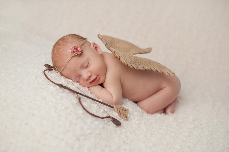 A baby is sleeping on the ground with wings.