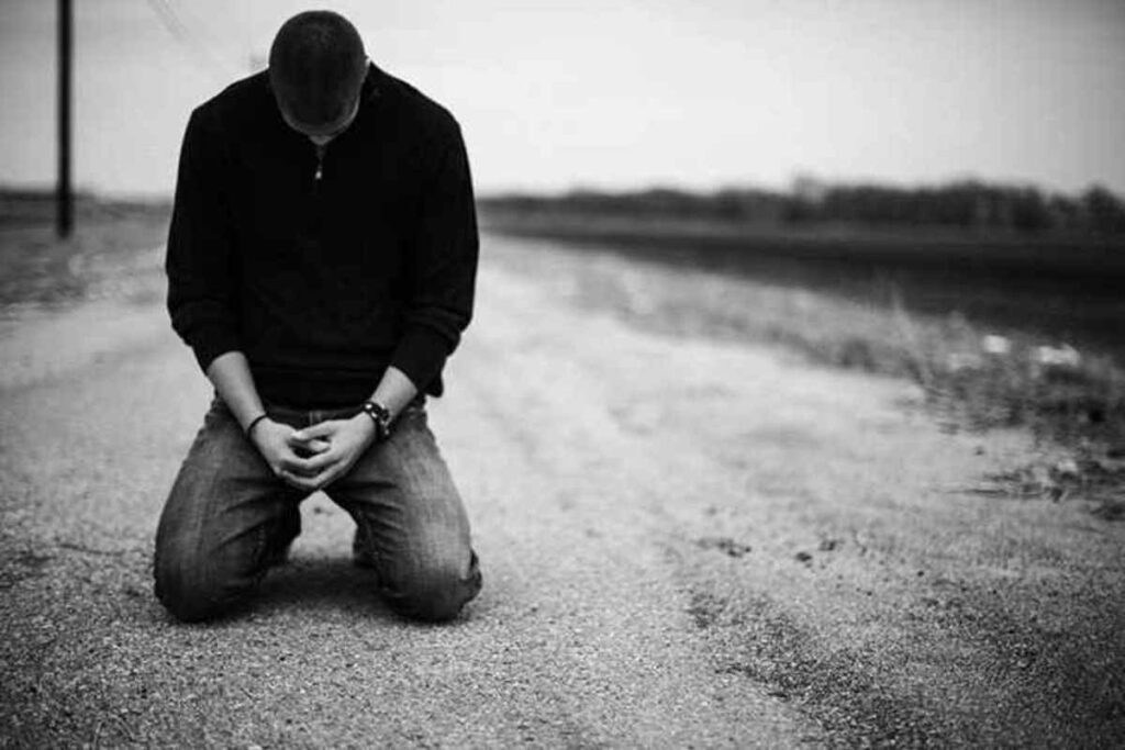 A man kneeling down on the side of a road.