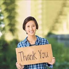 A woman holding up a sign that says " thank you ".