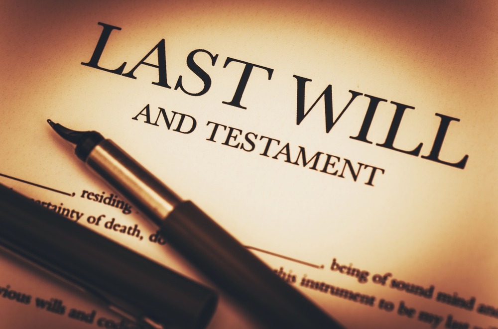 A pen and paper with the words " last will and testament ".