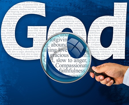 A person holding a magnifying glass over the word god.