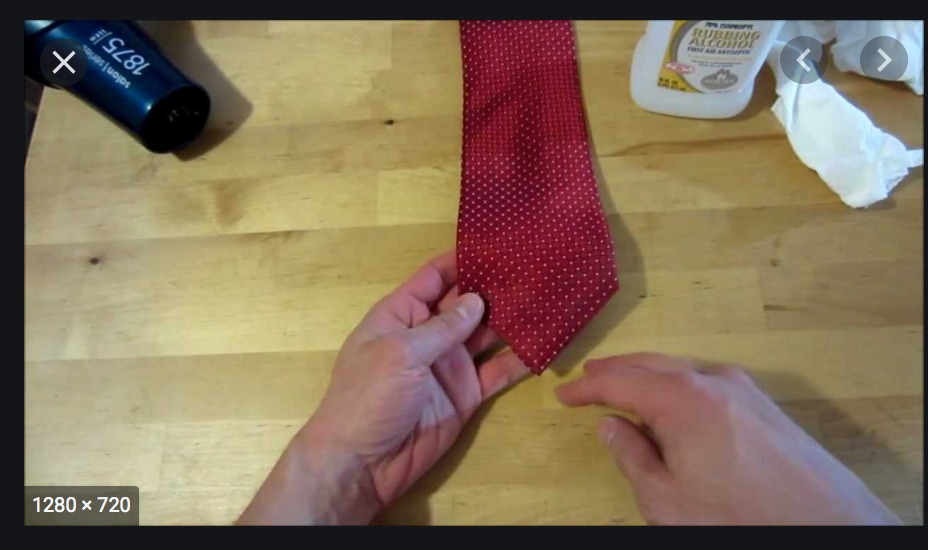 A person is folding the tie into a square.
