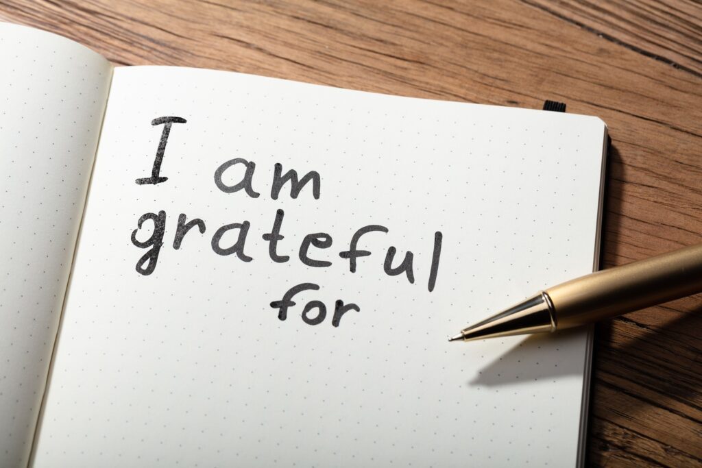 A pen and notebook with the words " i am grateful for ".
