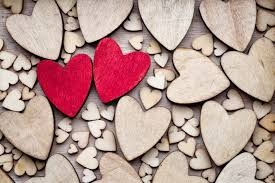 Two wooden hearts are sitting on a pile of wood.