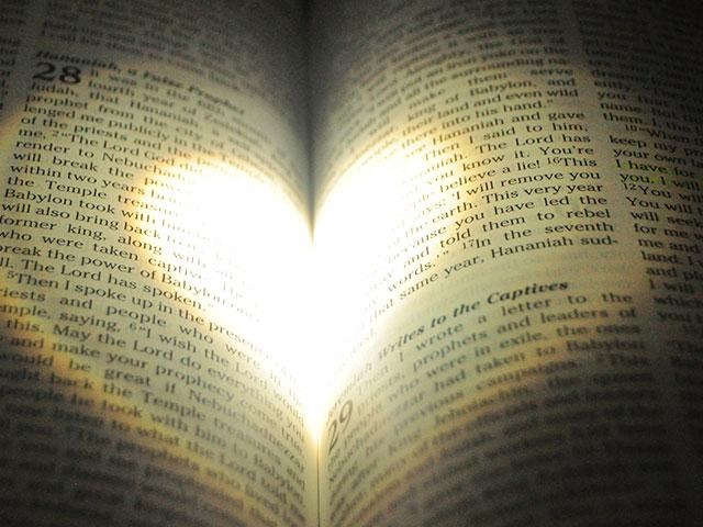 A book with the pages lit up in the shape of a heart.