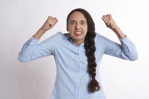 A woman with long hair is raising her arms.