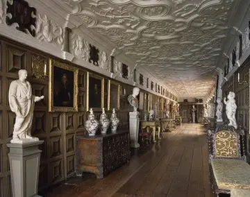 A long hallway with many statues and paintings on the walls.